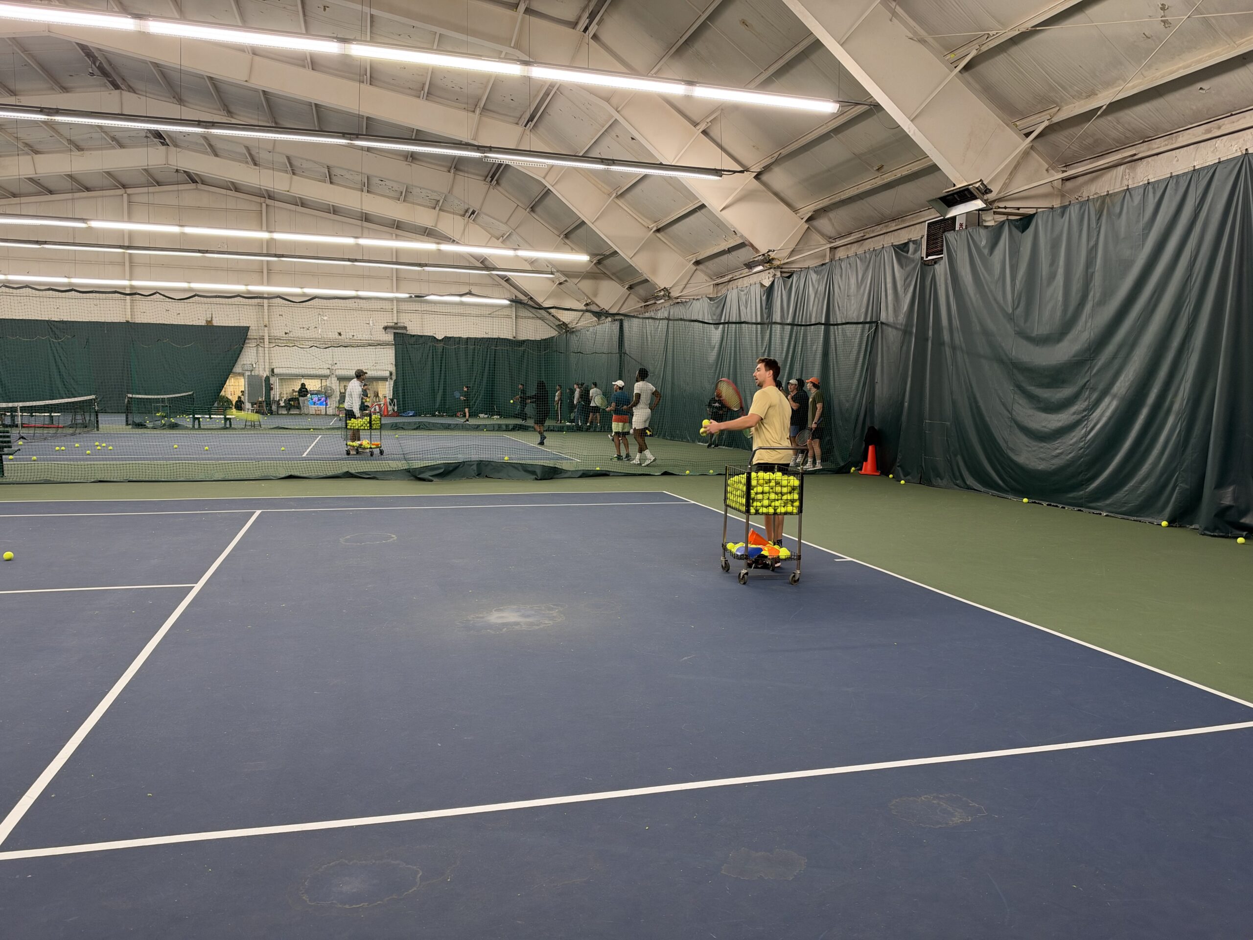 Jake coaching beside a basket of tennis balls during the October 10 clinic