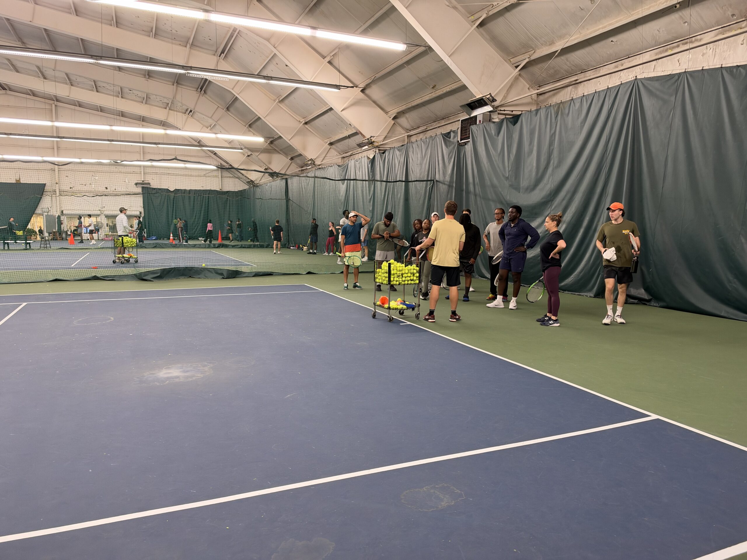 Players gathering with Jake on an indoor tennis court at Twin Lakes during the October 10 clinic